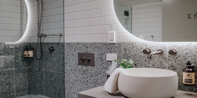 The shower area in Plaza Premium Lounge at Sydney Airport features a modern basin, wall-mounted fixtures, and complimentary toiletries.