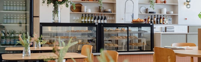 The Plaza Premium Arrivals Lounge at Sydney Airport features a self-serve food area with pastries, bottled water, and a selection of wines.