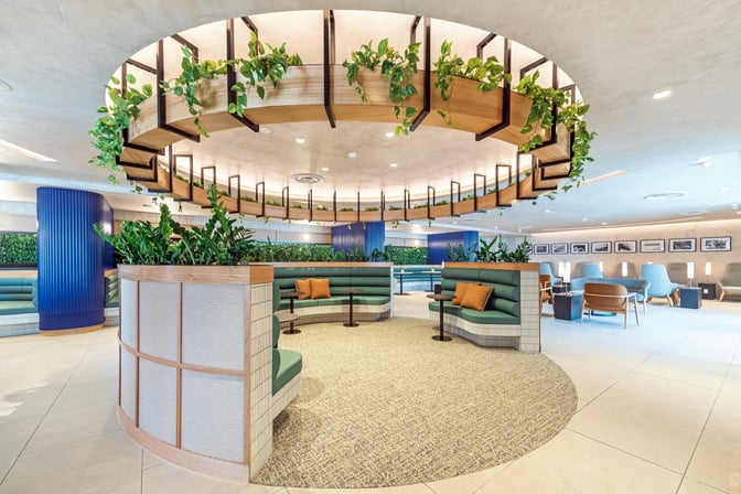 The SkyTeam Lounge at Sydney Airport features booth seating with tables, surrounded by greenery and offering a comfortable waiting area.