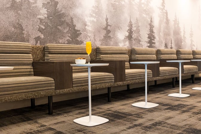 The seating area in the Escape Lounge at Syracuse Hancock International Airport features cushioned benches with individual tables for refreshments.