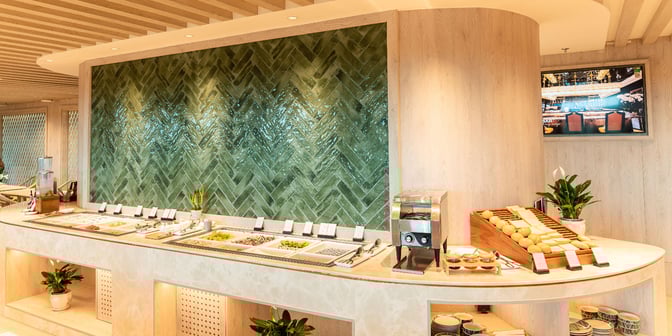 The SH Premium Lounge at Tan Son Nhat International Airport features a self-serve food station with various fresh ingredients and bread.