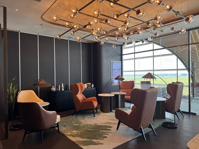 Seating area in Plaza Premium First Lounge at Techo International Airport features comfortable chairs and tables with views of the airfield.