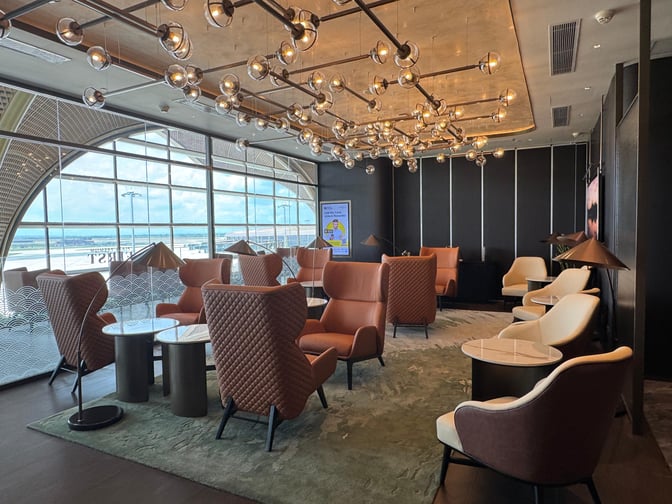 The seating area at Plaza Premium First, Techo International Airport, features comfortable chairs and tables with expansive airport views.