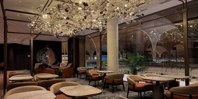 The seating area in Plaza Premium First at Techo International Airport offers tables and chairs with views of the terminal.