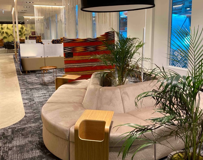The Scanderbeg Lounge at Tirana International Airport features comfortable seating with integrated tables and decorative plants for a relaxing environment.