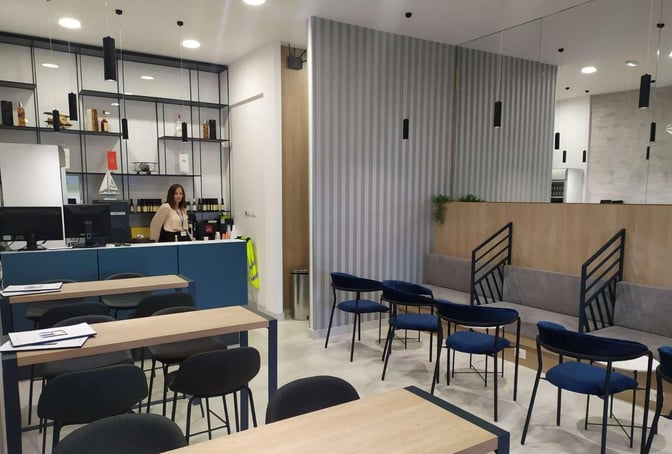 The business lounge at Tivat Airport features a reception desk, seating area, and shelves with various beverages.