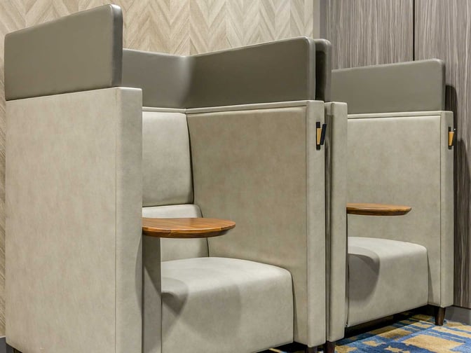 Semi-private seating booths in the Plaza Premium Lounge at Toronto Pearson offer individual tables for work or relaxation.
