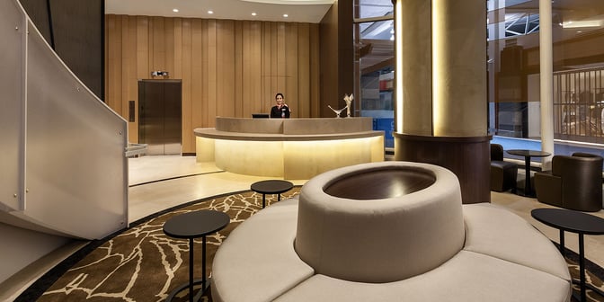 The reception area of Plaza Premium Lounge at Vancouver International Airport features a circular seating arrangement and a staffed check-in desk.