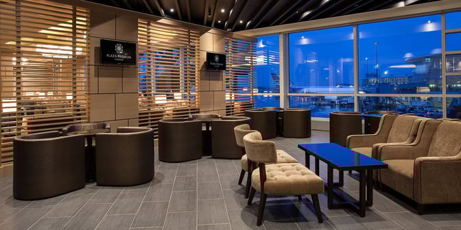 The Plaza Premium Lounge at Vancouver International Airport features comfortable seating areas with views of the airport tarmac through large windows.