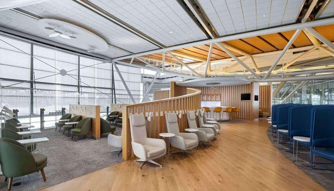 The SkyTeam Lounge at Vancouver International Airport features diverse seating options, including individual chairs and booths, with adjacent tables for convenience.