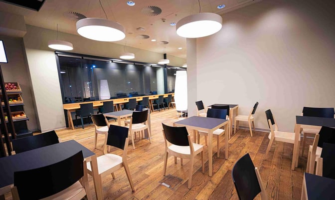 The Austrian Business Lounge at Vienna Airport features a seating area with tables and chairs, and a counter with power outlets.