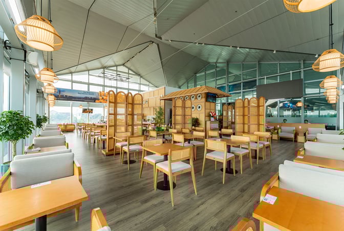 The SH Premium Lounge at Vinh Airport features a spacious seating area with tables and chairs, offering a comfortable waiting environment.