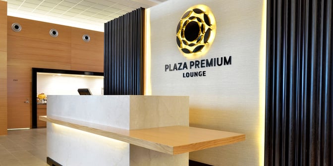 The reception area of Plaza Premium Lounge at Winnipeg Airport features a check-in counter and visible lounge signage.