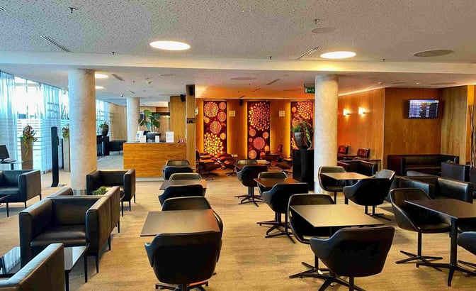 The Executive Lounge at Wroclaw–Nicolaus Copernicus Airport features seating areas with tables and chairs, and a reception desk.