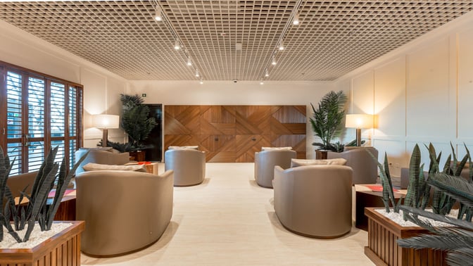 The seating area in the Primeclass Lounge at Zagreb Airport features comfortable chairs and decorative plants, providing a relaxing environment.