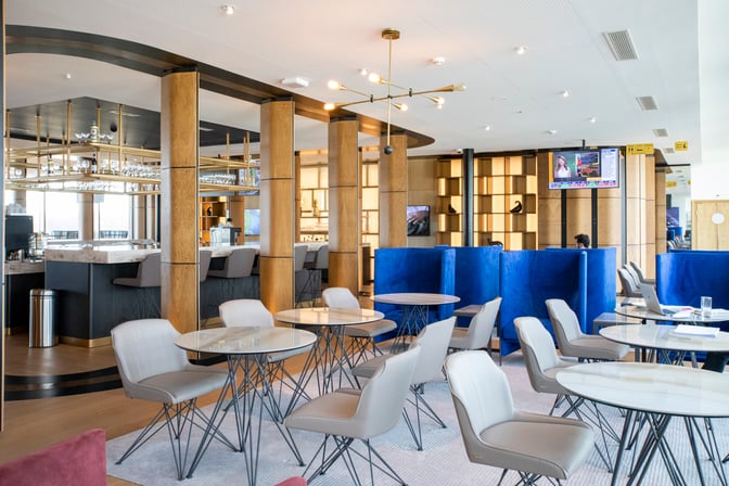 The Primeclass Lounge at Zurich Airport features a bar area with counter seating and a seating area with tables and chairs.