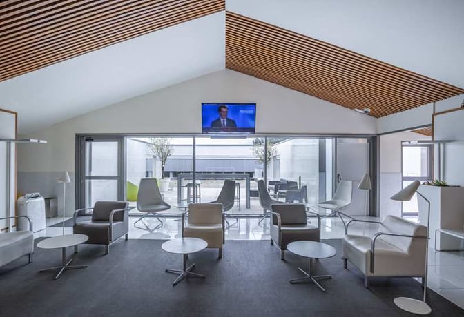 The VIP Lounge at A Coruña Airport features a seating area with armchairs, small tables, and a television for passenger relaxation.