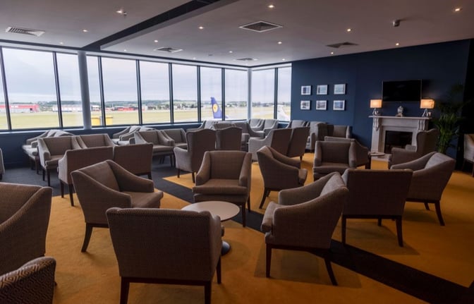The Northern Lights Executive Lounge at Aberdeen International Airport features comfortable seating with views of the runway through large windows.