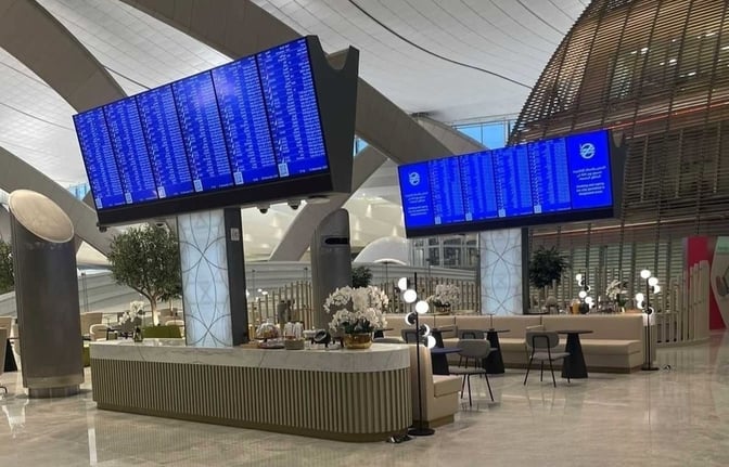 The Pearl Lounge at Abu Dhabi International Airport features seating areas with tables and a large flight information display screen.