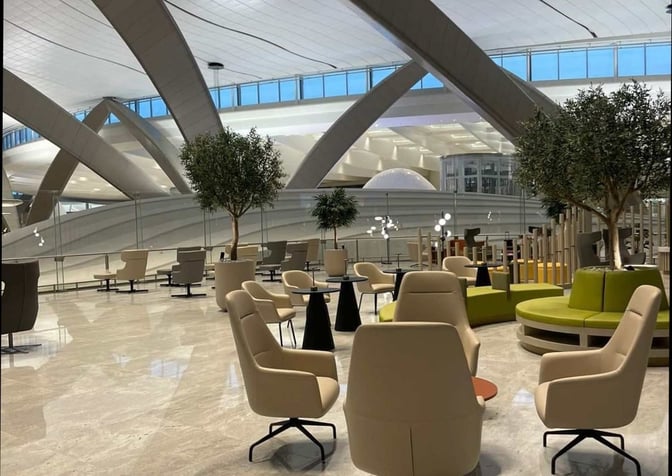 The seating area at Pearl Lounge, Abu Dhabi International Airport, features comfortable chairs and tables with views of the terminal.