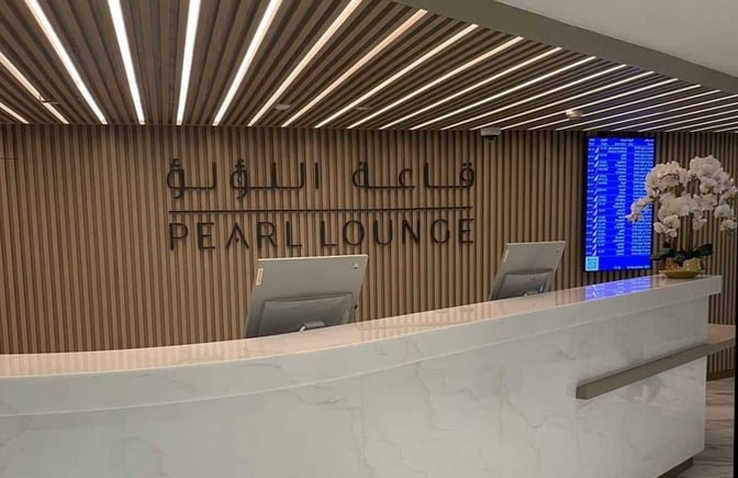 The reception area of the Pearl Lounge at Abu Dhabi International Airport features check-in counters and a flight information display.