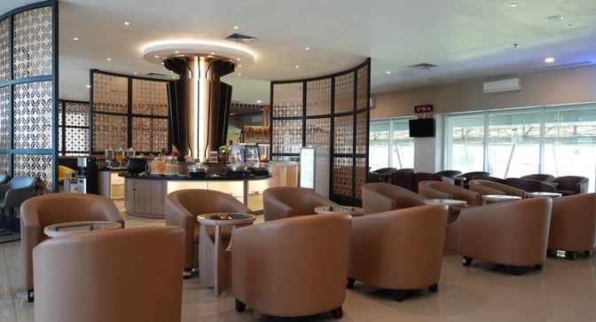 The Concordia Lounge at Achmad Yani International Airport features a seating area with armchairs and a self-serve food station.