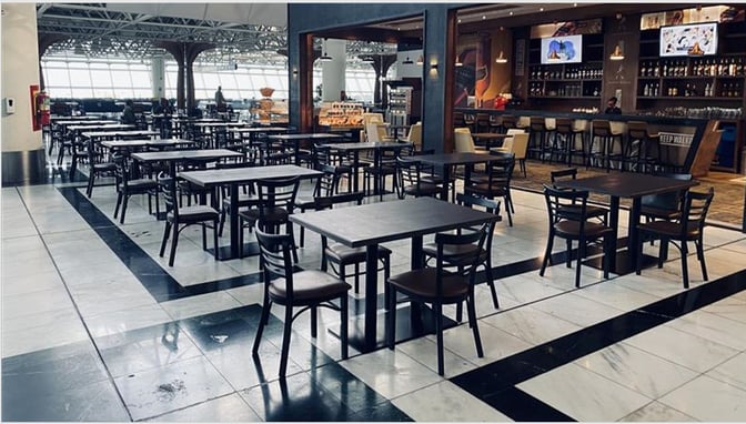 The Plaza Premium Lounge at Addis Ababa Bole International Airport features a spacious seating area with tables and a bar offering beverages.