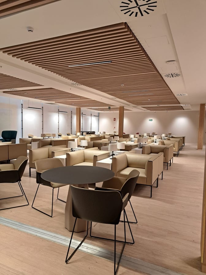 The Retiro VIP Lounge at Madrid Barajas Airport features a spacious seating area with tables, chairs, and individual lamps for travelers.