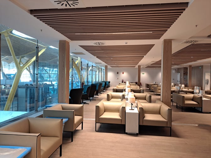 The Retiro VIP Lounge at Madrid Barajas Airport features spacious seating with individual tables and views of the terminal through large windows.