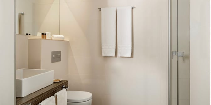 The bathroom in The Hub at Madrid Barajas Airport features a sink, toilet, and shower with complimentary toiletries and towels.