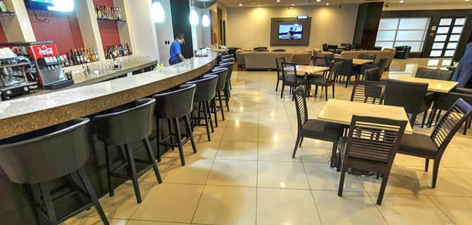 The Aeroportos VIP Club at José Joaquín de Olmedo International Airport features a bar with counter seating and adjacent dining tables.