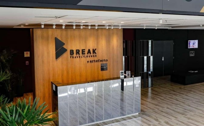 The Break Travel Lounge entrance at Afonso Pena International Airport features a reception desk and signage, welcoming travelers to the lounge.