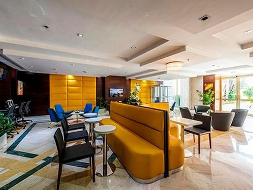 The Agadir Aspire Executive Lounge features varied seating options, including booth and table arrangements, with views of the airport entrance.