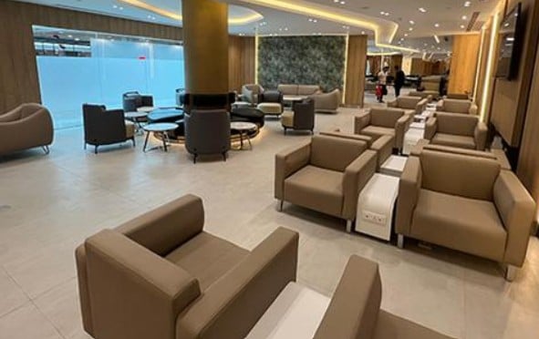 The seating area in Ahlein - Emerald Lounge at Cairo International Airport features armchairs and tables, providing a comfortable waiting space for travelers.