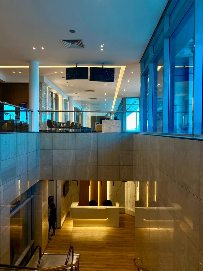 The Ahlein Premium Lounge at Cairo International Airport features a reception area and upstairs seating with tables and chairs.