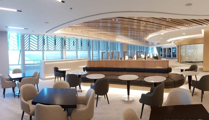 The Ahlein Premium Lounge at Cairo International Airport features a spacious seating area with tables and chairs for travelers.