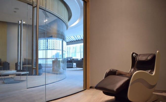 The Ahlein Premium Lounge at Cairo International Airport features a massage chair and a seating area visible through glass doors.