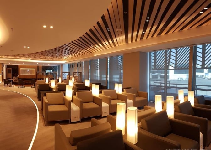 The seating area in Ahlein Premium Lounge at Cairo International Airport features comfortable armchairs with individual lamps and airport views.