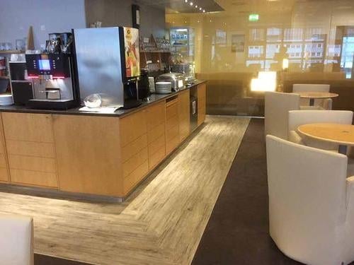 The Air France Lounge at Frankfurt Airport features a self-serve beverage station with coffee machines and seating for dining.