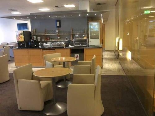 The Air France Lounge at Frankfurt Airport features a self-serve food area with tables and chairs for dining.