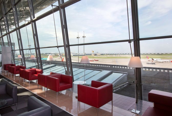 Seating in Hamburg Airport Lounge offers views of the runway, featuring armchairs and tables by large windows.