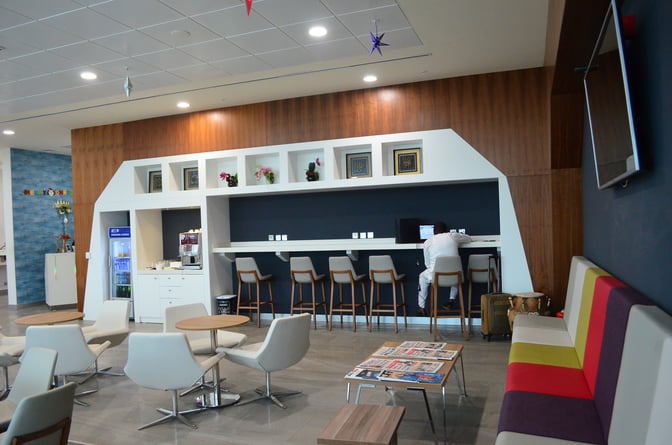 The Akwaaba Lounge at Kotoka International Airport features a seating area with tables, a bar counter, and complimentary refreshments.