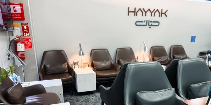 The seating area in Hayyak Lounge at Al-Jouf International Airport features comfortable chairs with side tables and individual lamps.