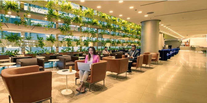 Seating area in Al Maha Lounge at Doha Hamad International Airport features armchairs and tables with a backdrop of vertical greenery.