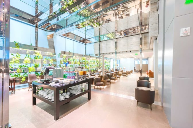 The Al Maha Lounge at Doha Hamad International Airport features a self-serve beverage station with seating areas for relaxation and dining.