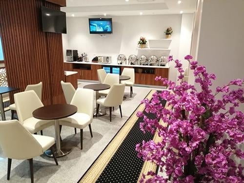 The Pearl Lounge at Alexandria International Airport features a dining area with tables, chairs, and a self-serve buffet station.