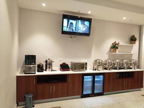 The Pearl Lounge at Alexandria International Airport features a self-serve food area with chafing dishes, beverage machines, and a television.