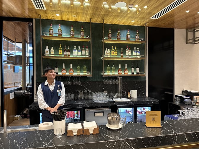 The bar at Extime Business Lounge, Almaty International Airport, offers a selection of spirits with counter service and seating.