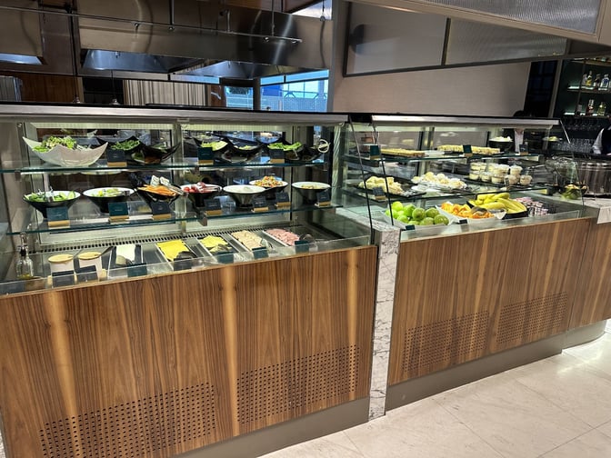 The self-serve food area at Extime Business Lounge offers a variety of salads, cheeses, fruits, and desserts.