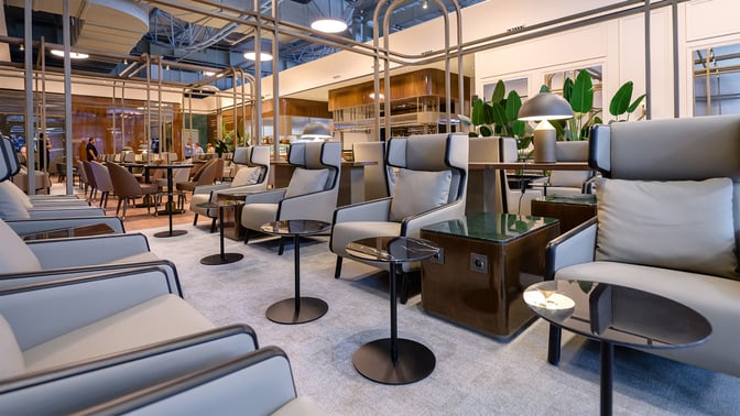 The Extime Business Lounge at Almaty International Airport features comfortable seating with small tables and power outlets for travelers.
